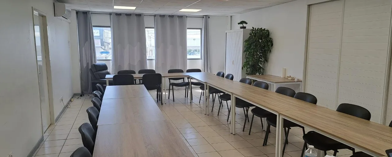 La salle Zen et Pro avec ses tables en U, ses rideaux gris et son fauteuil près des fenêtres