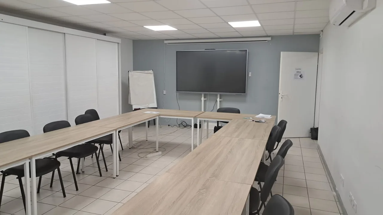 Vue de la salle Zen et Pro face au grand écran et au paperboard, avec les tables en U